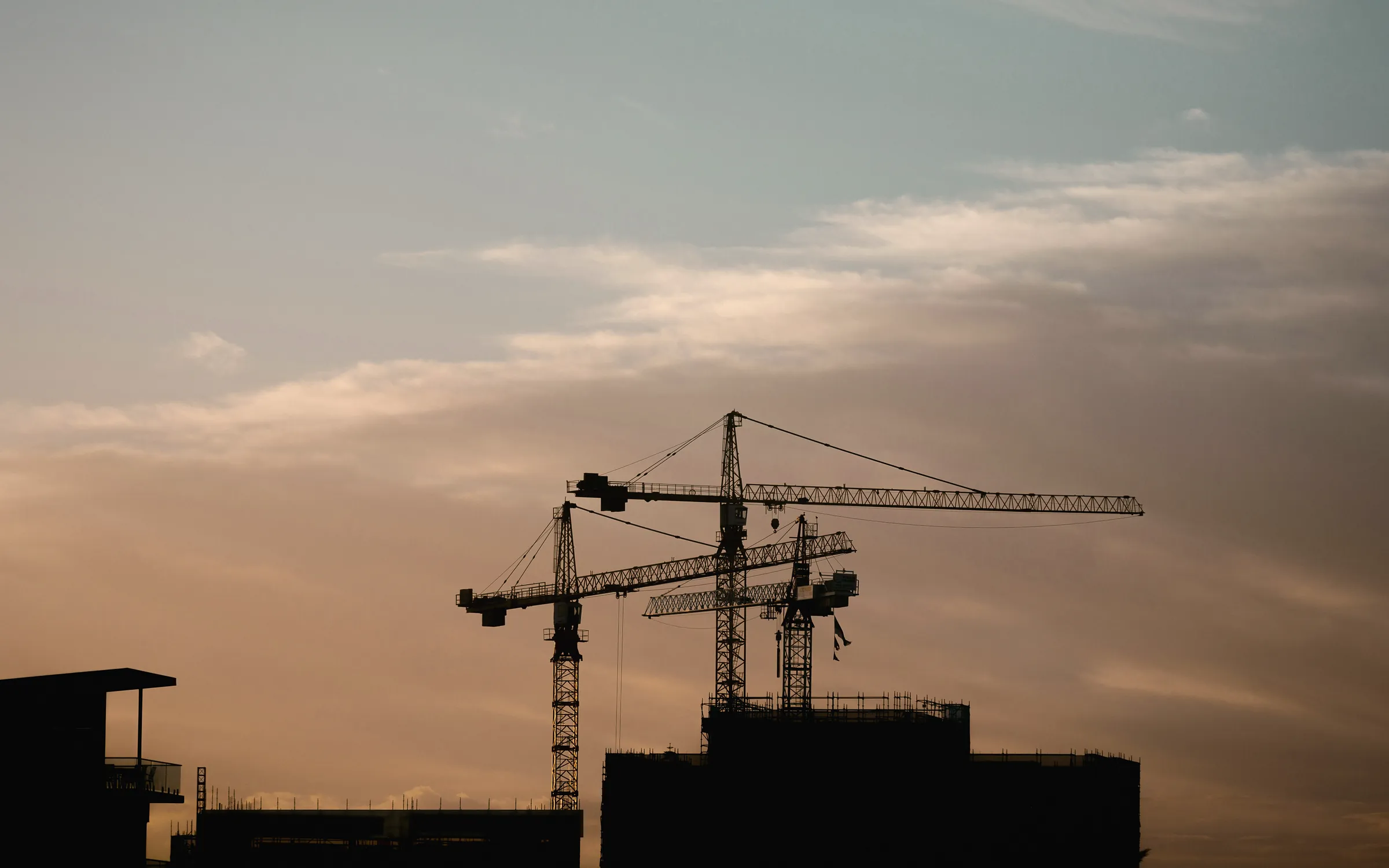 Tower cranes over a building under construction at dusk