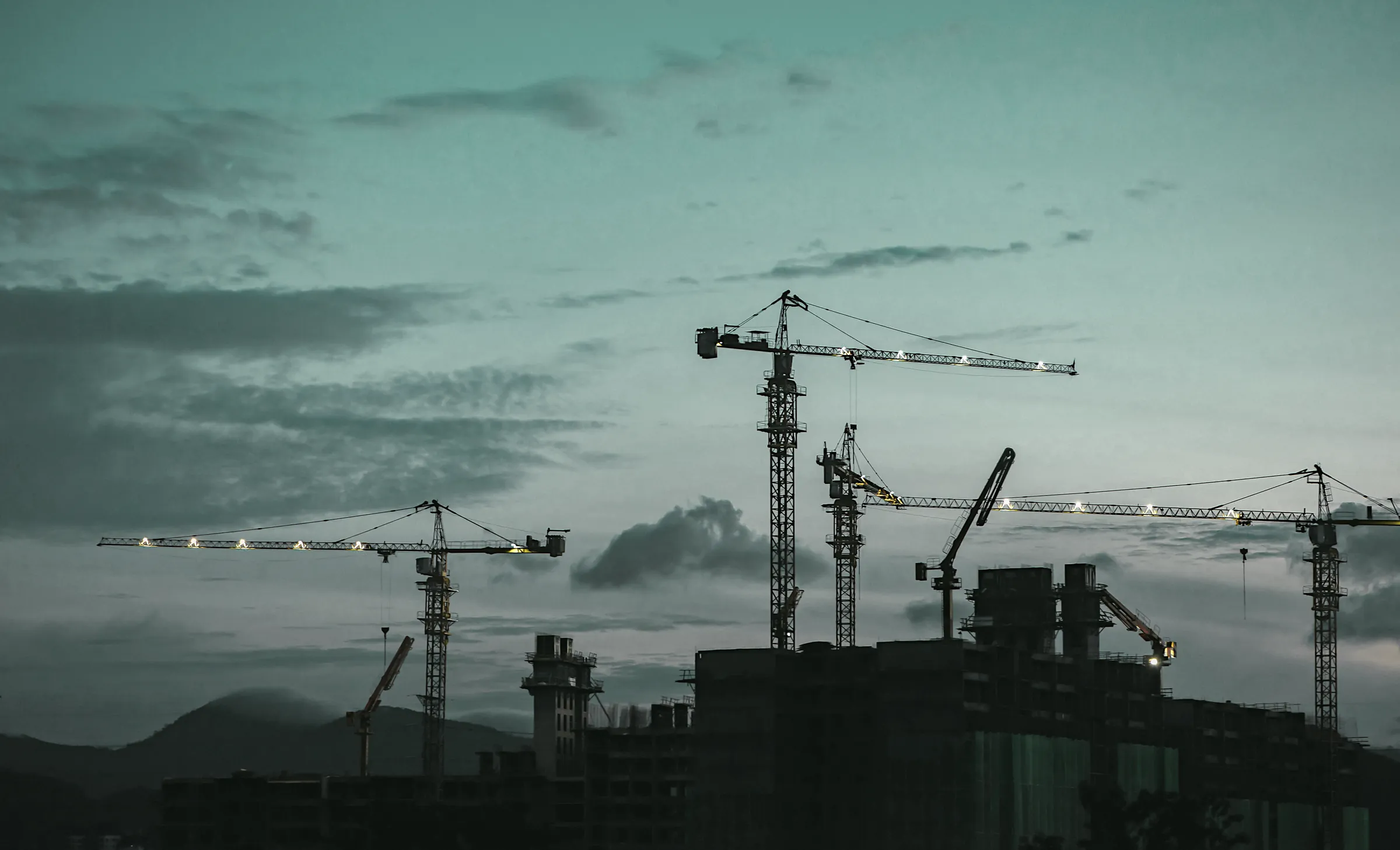 Tower cranes over apartment buildings at dusk